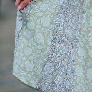 May include: A light green and grey skirt with a floral print. The skirt is made of a lightweight fabric and has a flowing silhouette.