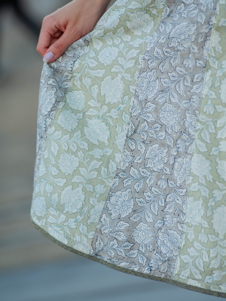May include: A light green and grey skirt with a floral print. The skirt is made of a lightweight fabric and has a flowing silhouette.