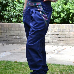 May include: A pair of dark blue pants with a colorful patterned waistband. The pants have a loose fit and are cuffed at the ankles.