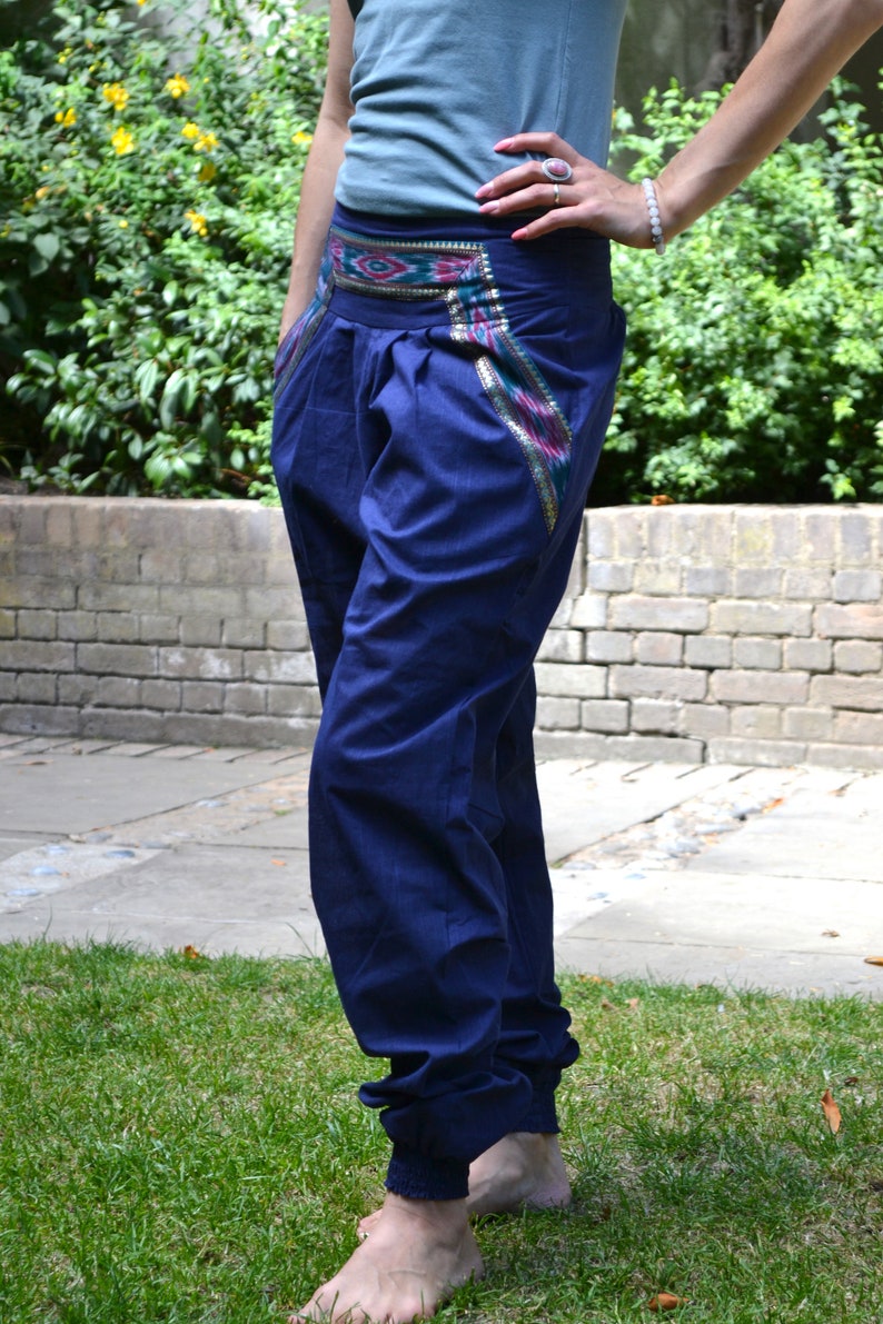 May include: A pair of dark blue pants with a colorful patterned waistband. The pants have a loose fit and are cuffed at the ankles.