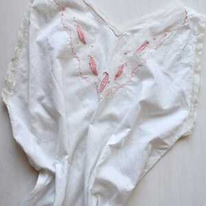 May include: White cotton nightgown with a pink embroidered neckline featuring a scalloped edge and floral designs.
