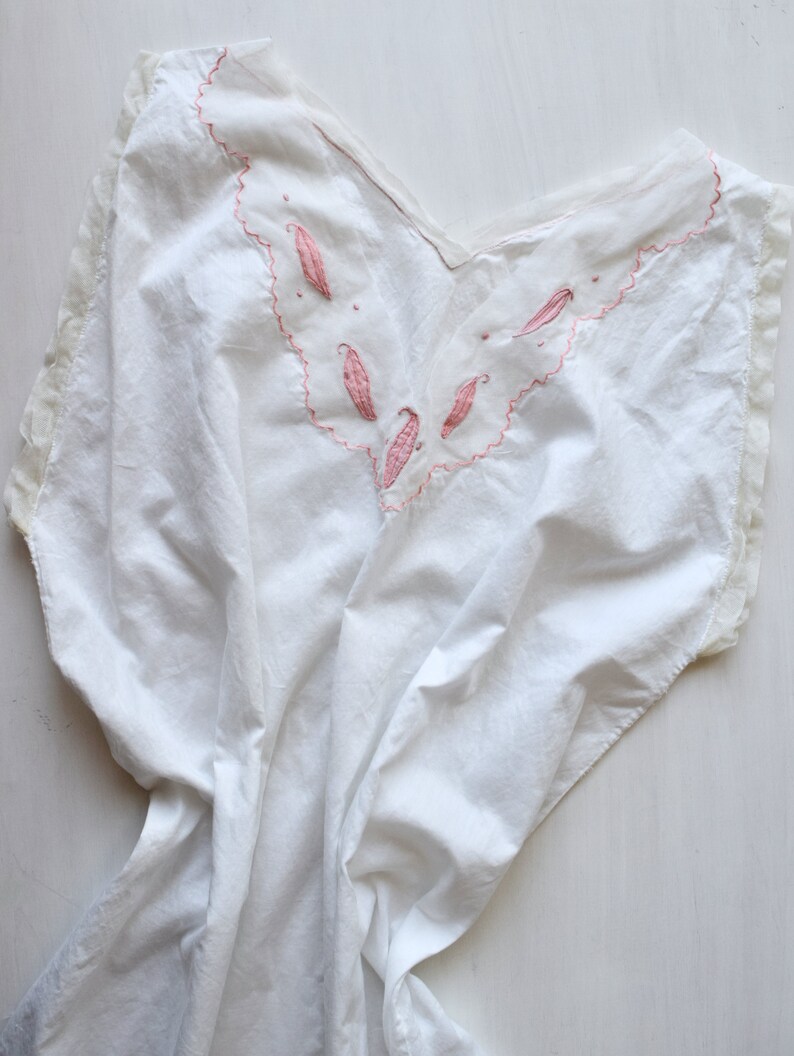 May include: White cotton nightgown with a pink embroidered neckline featuring a scalloped edge and floral designs.