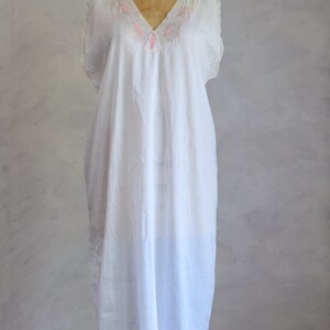 May include: A white cotton nightgown with pink embroidery around the neckline. The nightgown is on a dress form.
