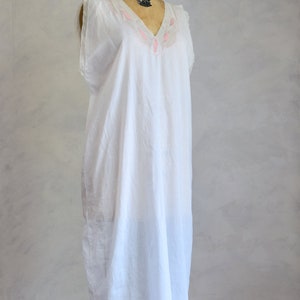 May include: A white cotton nightgown with pink embroidered leaves around the neckline. The nightgown is sleeveless and has a V-neck.