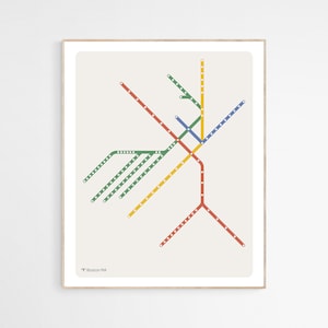 May include: A minimalist style subway map of the Boston, MA public transportation system. The map features the different lines in red, blue, green, and yellow. The lines are represented by thin lines with small white dots along the lines. The map is on a light beige background and is framed in a light wood frame. The text "T Boston MA" is in the bottom left corner of the map.