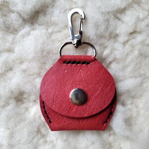 May include: A red leather keychain with a silver clasp and a silver button closure.