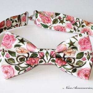 May include: A white bow tie with a floral pattern featuring pink roses and green leaves.