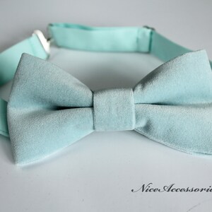 May include: A light blue velvet bow tie with an adjustable strap. The bow tie is made of a soft, luxurious fabric and is perfect for adding a touch of elegance to any outfit.