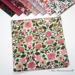 Könnte beinhalten: Ein weißes Baumwolltaschentuch mit einem Blumenmuster aus rosa Rosen und grünen Blättern. Das Taschentuch hat einen weißen Hintergrund und einen grünen Rand.