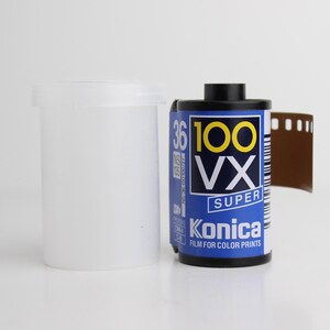 May include: A Konica VX Super 100 film roll with a blue and white label, a white plastic film canister, and a strip of exposed film. The film roll is labeled "36" and "Film for Color Prints."