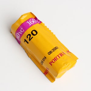 May include: A yellow roll of 120 film with the text "120" and "PORTRA PC" printed on it. The film is labeled as "ISO VC 160" and has an expiration date of "08/2001".