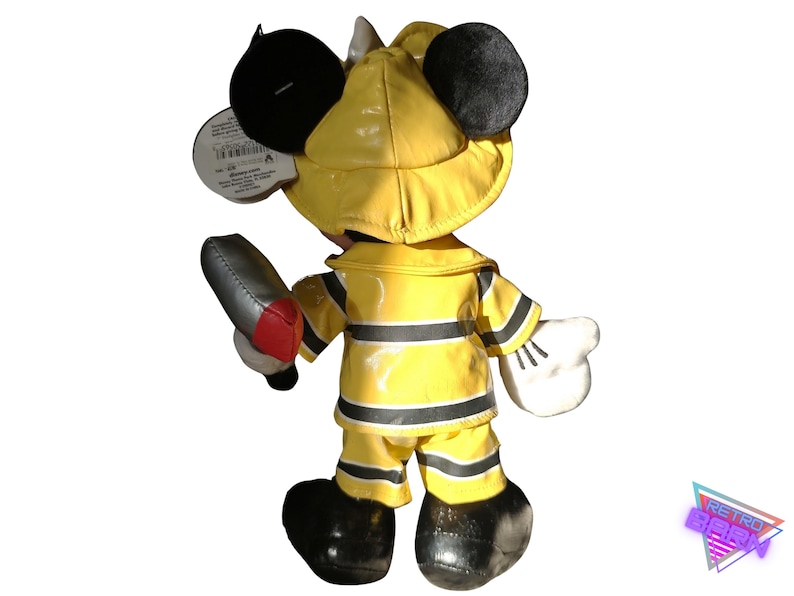 Puede incluir: Una figura de peluche de Mickey Mouse vestido de bombero, con abrigo, pantal&oacute;n y casco amarillos. La figura sostiene una herramienta de bombero plateada y roja. Las orejas y los zapatos negros completan el look. Una etiqueta est&aacute; adjunta.