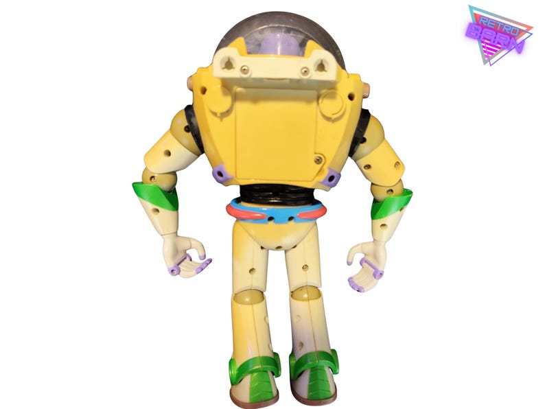 May include: A yellow and off-white Buzz Lightyear action figure with green and purple accents. The toy robot has a clear helmet and is standing with its arms at its sides. The Retro Geek logo is in the upper right corner.