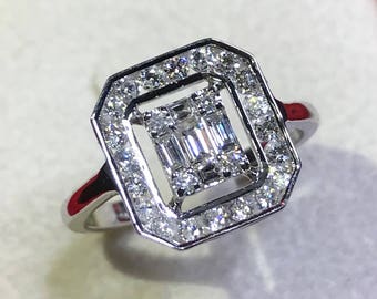 Può includere: Un anello di fidanzamento in oro bianco con un diamante centrale di forma quadrata circondato da un alone di diamanti più piccoli.