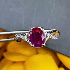 Può includere: Un anello d'argento con un grande rubino ovale e diamanti più piccoli incastonati in una fascia attorcigliata.