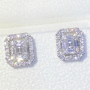 May include: A pair of silver earrings with a square shape. Each earring features a large, rectangular, baguette-cut diamond surrounded by smaller round diamonds.