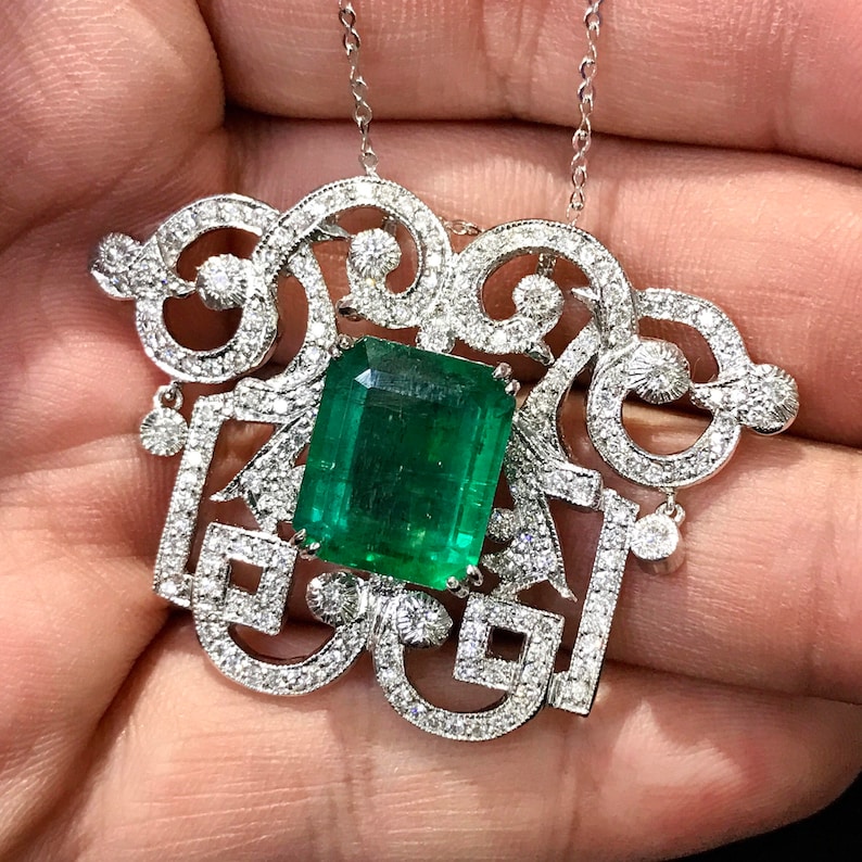 May include: A delicate silver necklace with a large emerald green gemstone set in a intricate diamond-encrusted design.