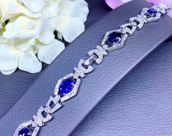 Puede incluir: Un brazalete de plata con un diseño geométrico adornado con zafiros azules y diamantes.