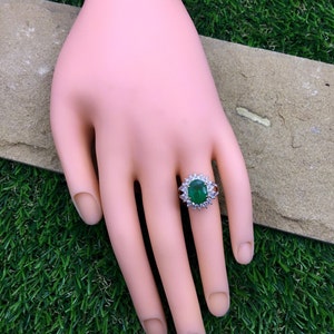 May include: A silver ring with a large oval-shaped green gemstone surrounded by smaller diamonds.
