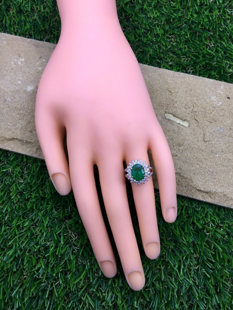 May include: A silver ring with a large oval-shaped green gemstone surrounded by smaller diamonds.