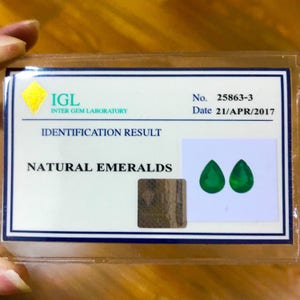May include: A certificate from the IGL (Inter Gem Laboratory) stating that the two pear-shaped gemstones are natural emeralds. The certificate number is 25863-3 and the date is 21/APR/2017.