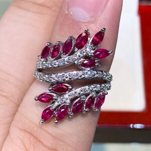 May include: A silver ring with a design of two intertwining branches set with red rubies and white diamonds.