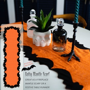 May include: A black and orange bat-shaped table runner with a scalloped edge. The text "Batty Mantle Scarf" is printed on the runner. The text "Great as a fireplace mantle scarf or a festive table runner!" is also printed on the runner. The kit includes laser-cut bats.