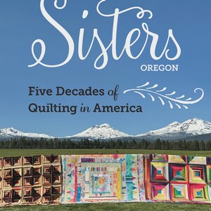 May include: Book cover titled "Sisters Oregon" with text "Five Decades of Quilting in America" and the author's name, Jean Wells. The image shows three colorful quilts on a grassy field with snow-capped mountains and a blue sky.