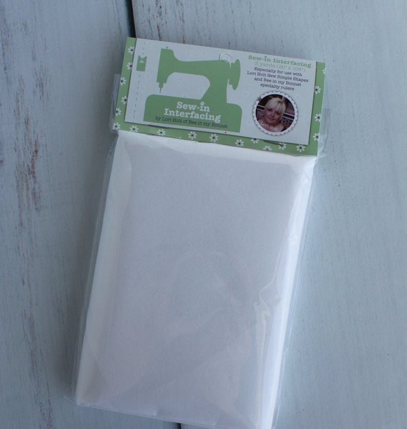 Puede incluir: Un paquete blanco de entretela termoadhesiva con una etiqueta verde que dice "Sew-in Interfacing by Lert Molt of Dee in my Bonnet". La etiqueta tambi&eacute;n tiene una m&aacute;quina de coser y una foto de una mujer.