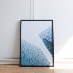 A photograph of a modern building with a glass facade.  Looking up from the bottom of a Reykjavik skyscraper. The blue-toned glass gives it a light and minimalist feel.