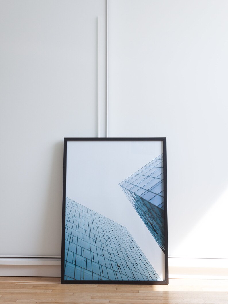 A photograph of a modern building with a glass facade.  Looking up from the bottom of a Reykjavik skyscraper. The blue-toned glass gives it a light and minimalist feel.