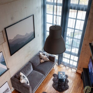 A modern living room with several framed pictures on the walls, including a photo of the Reykjavik skyscraper by Minumo. The blue glass gives the space a light and minimalist feel, which is perfect for a modern home.