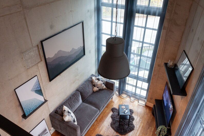 A modern living room with several framed pictures on the walls, including a photo of the Reykjavik skyscraper by Minumo. The blue glass gives the space a light and minimalist feel, which is perfect for a modern home.