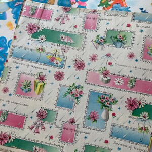 Puede incluir: Una hoja de papel de regalo vintage con fondo blanco y un patr&oacute;n repetitivo de dise&ntilde;os florales rosas, azules y verdes. El papel tiene el texto "Showers of Happiness" impreso en &eacute;l.
