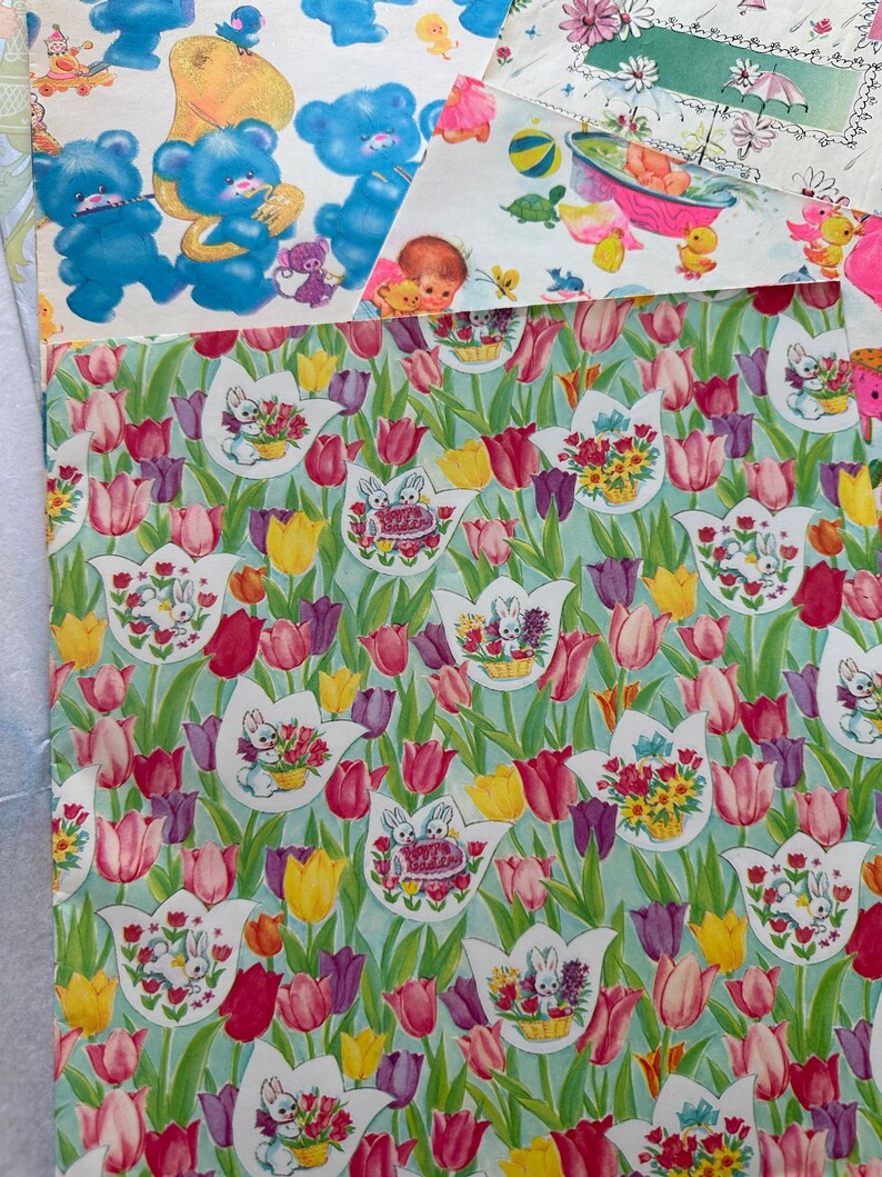 Puede incluir: Un dise&ntilde;o de papel de regalo vintage con un patr&oacute;n repetitivo de tulipes rosas, moradas y amarillas con conejos blancos que sostienen cestas de flores sobre un fondo azul claro.