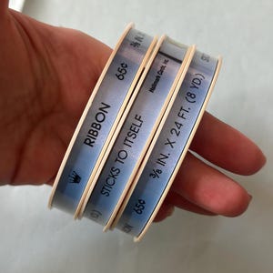 May include: Three rolls of blue and white ribbon with the text "RIBBON", "STICKS TO ITSELF", "3/8 IN. X 24 FT. (8 YD.)", and "65¢" printed on them.