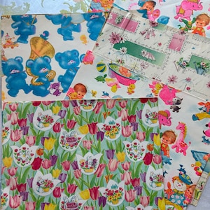 Puede incluir: Surtido de papel de regalo para baby shower con diferentes patrones. Una hoja tiene un fondo azul con ositos de peluche tocando instrumentos. Otra hoja tiene un fondo rosa y blanco con un beb&eacute; en una ba&ntilde;era. Una tercera hoja tiene un fondo verde con tulipes y conejos. El texto en una hoja dice "Showers of happiness".
