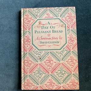 May include: Vintage book titled "A Day of Pleasant Bread, A Christmas Story by David Grayson." The cover features a repeating pattern in red and green, with the title in a decorative frame.