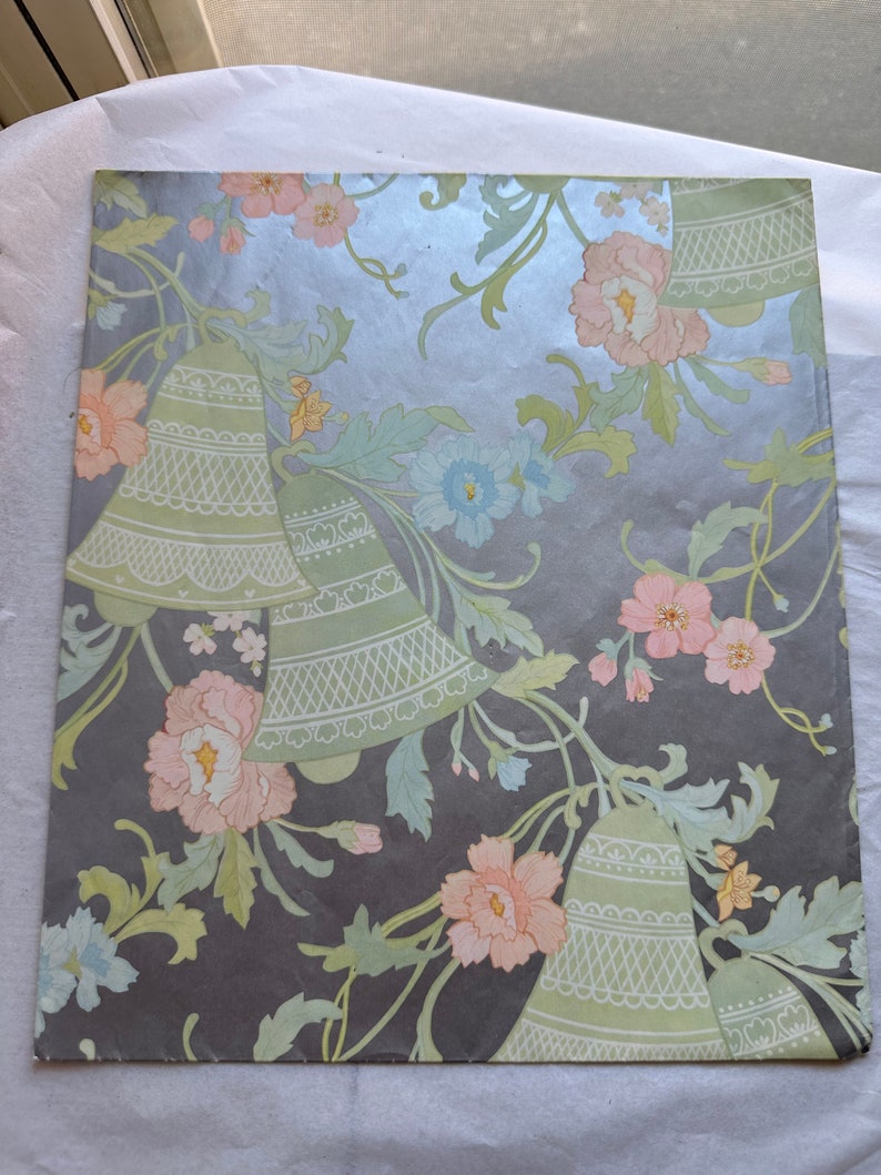 Puede incluir: Papel de regalo floral vintage con fondo plateado. El papel presenta un patr&oacute;n repetitivo de campanas verdes, flores rosas y blancas y hojas verdes.