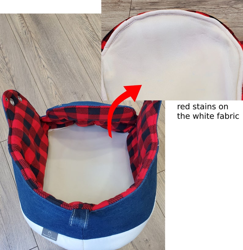 May include: A blue denim and white pet bed with a red and black plaid interior. The bed has a rounded shape with ear-like flaps. The interior has red stains on the white fabric.