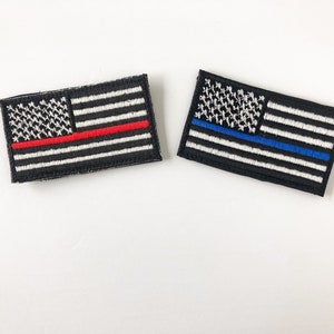 May include: Two embroidered American flag patches. The first patch has a red stripe across the stars and stripes. The second patch has a blue stripe across the stars and stripes.