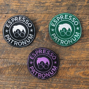 May include: Three round embroidered patches with the text "Espresso Patronum" in white. The patches are black, green, and purple. Each patch features a white silhouette of a person with glasses and a lightning bolt on their forehead.
