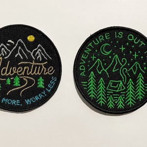May include: Two black embroidered patches featuring a mountain and forest design. The first patch reads "Adventure Explore More, Worry Less" in gold and blue lettering. The second patch reads "Adventure is Out There" in white lettering with a crescent moon, stars, and a tent.