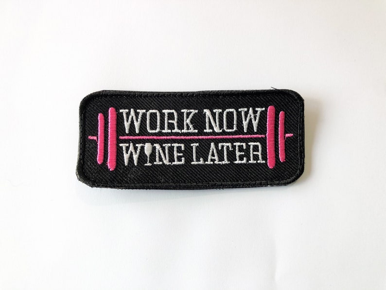 Peut inclure: Patch brod&eacute; noir avec du texte blanc qui dit "Work Now Wine Later" avec un graphique de barre rose.