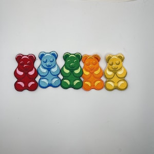 May include: Five gummy bear shaped patches in different colors: red, blue, green, orange, and yellow. The patches are all the same size and shape, and they are arranged in a row.