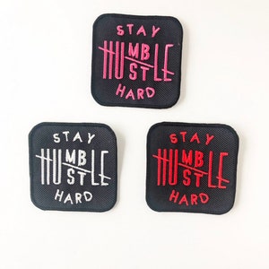 May include: Three black fabric patches with white and red embroidery. The patches feature the text "Stay Humble Hustle Hard" with a line through the word "Humble".