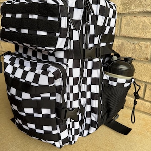 May include: A black and white checkered backpack with multiple compartments, including a side pocket for a water bottle. The backpack features black straps, buckles, and a black mesh water bottle holder. The design is a repeating checkerboard pattern.