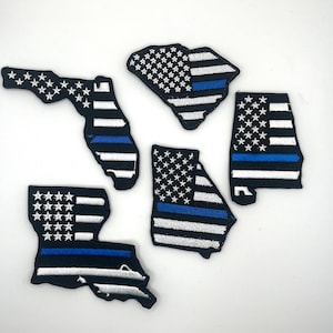 May include: Four embroidered patches in the shape of US states, Florida, Georgia, Alabama, and South Carolina. Each patch features a white and black American flag with a thin blue line across the bottom.