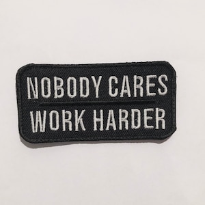 Peut inclure: Écusson brodé noir avec du texte blanc qui dit "Nobody Cares Work Harder".