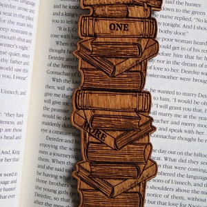 May include: A wooden bookmark with a stack of books design. The bookmark has the words "Just One More Chapter" on it.